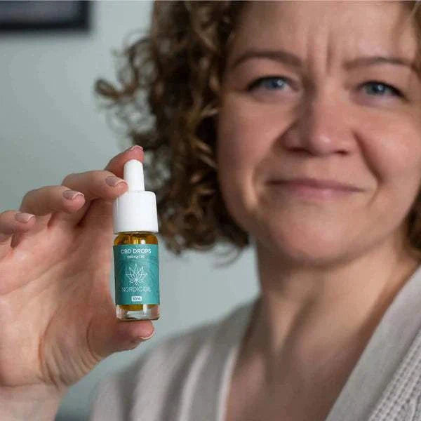 Frau hält Nordic Oil CBD Öl Plus 10% Flasche mit 1000mg CBD und MCT-Öl für bessere Aufnahme