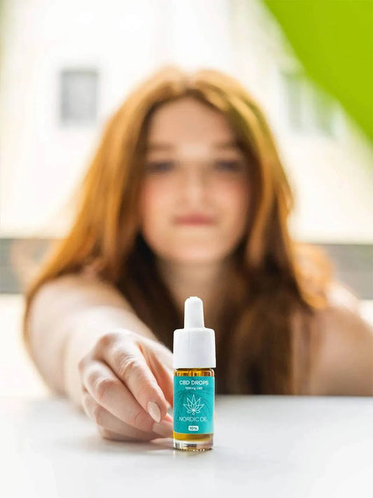 Frau präsentiert Nordic Oil CBD Öl Plus 10% in 10ml Flasche mit MCT-Öl für bessere Aufnahme